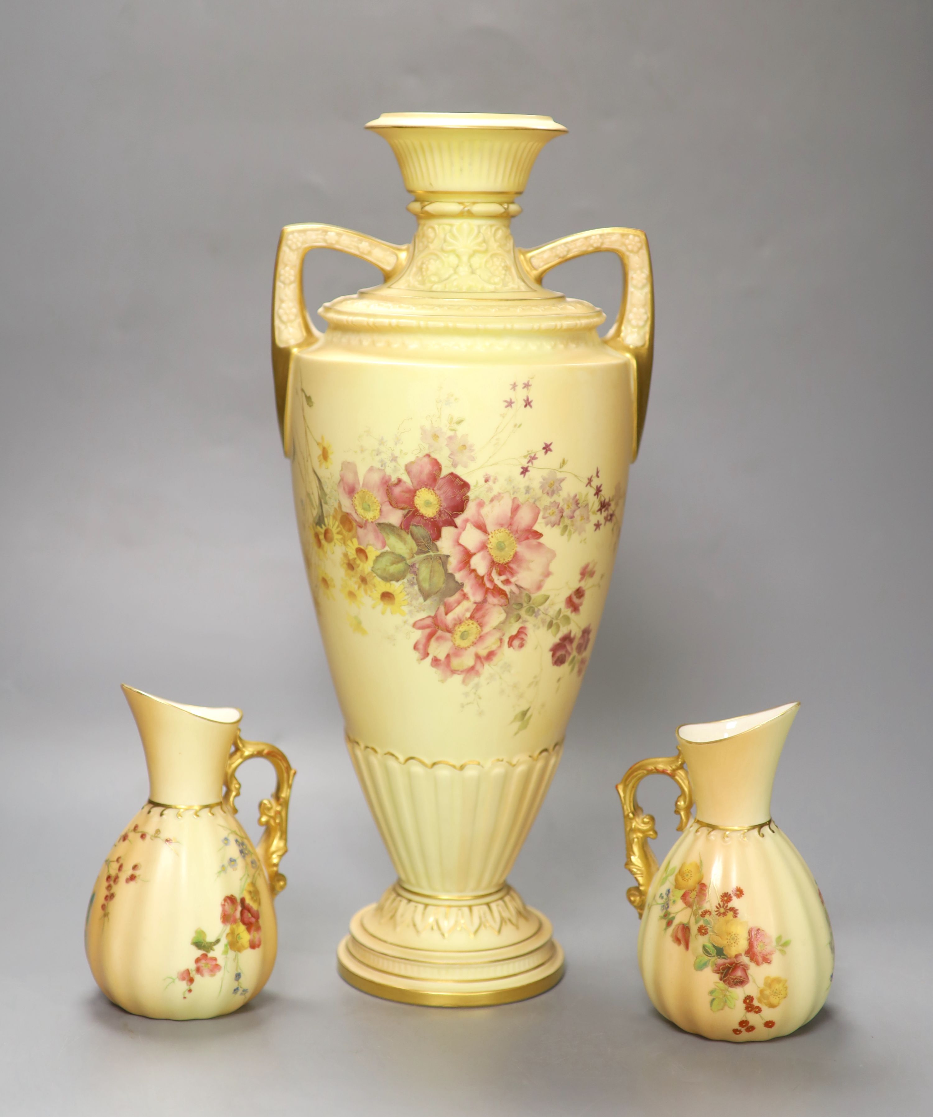 A Royal Worcester two-handled blush ivory vase, decorated with flowers, height 38cm, and a pair of similar jugs